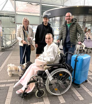 Amelia Reid (in wheelchair) and her partner, Samuel Sharp (second left), are met by her parents and her dog, Penny, at London Stansted Airport following their return to the UK on the Government´s first charter flight to evacuate British nationals from the Middle East